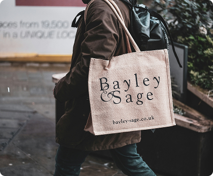 Person holding a branded jute shopping bag